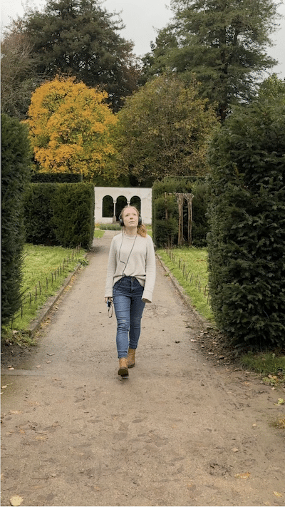 Woman walking towards camera on a path in formal gardens